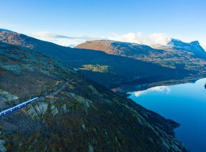 Narvik-Kiruna välillä liikennöivä juna kulkemassa vuonon juurella vuoren rinteellä.