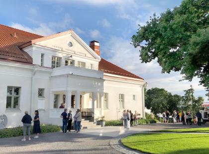 Turvään Pappilan valkoisen talon pihalla ihmsiä.